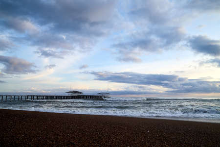 View from beach to water of sea, waves with white foam, pierce and sky with clouds in a nice eveningの写真素材