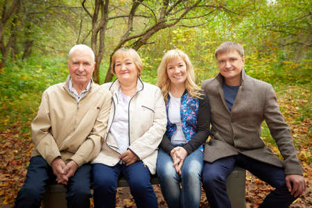 Grandmother and grandfather walking with adult children in nature. Mature couple and young couple...