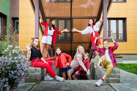 Group of fun children in stylish clothes near big modern house in the city in a summer, spring, or autumn dayの写真素材