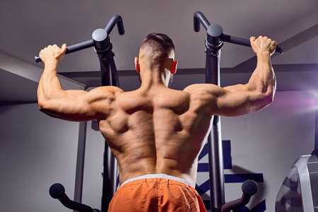 Handsome male bodybuilder in the gym. Big strong man during training in the gym. Guy with big...