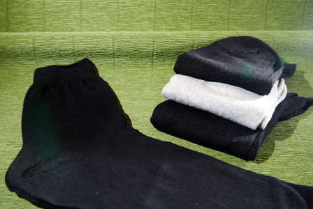 Several pairs of male socks on a green surface