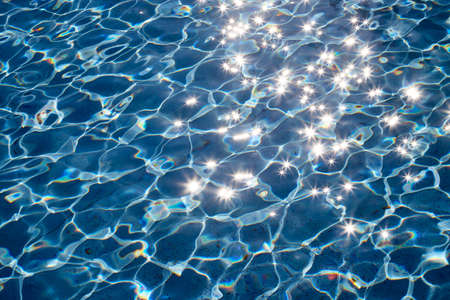 Blue water background with glitter under the sun