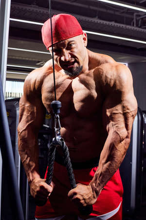 Handsome male bodybuilder in the gym. Big strong man during training in the gym. Guy with big...