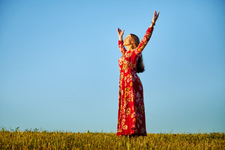 Beautiful woman or girl with magnificent figure and plastic movements walking and dancing in green field with trimmed grass in the setting sun during sunset with warm yellow lightの写真素材