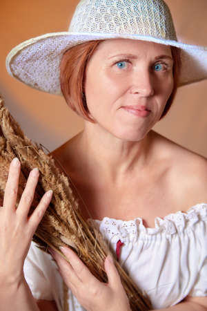 Portrait of ugle middle-aged woman with hat. A model posing in a rustic style in a Studioの写真素材