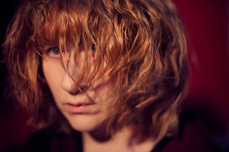 Portrait of serious sad tousled disheveled middle-aged woman on red background. Unprofessional...
