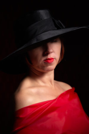 Portrait of ugle middle-aged woman with hat and red dress. Ugly model looking as lady posing in...