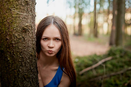 Beautiful young brunette woman with long hair in a forest pines and firs on a summer day