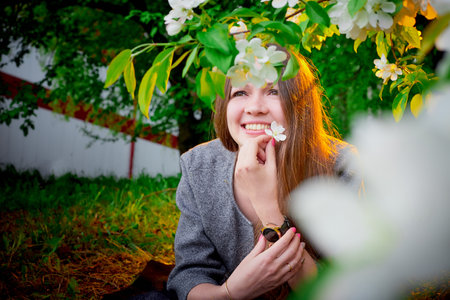 Outdoor portrait of a beautiful young girl near blossom apple trees with white flowers