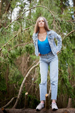 Beautiful young brunette woman with long hair in a forest pines and firs on a summer day