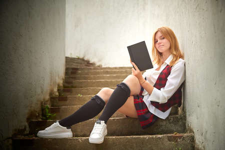 Young girl with short hair in a school checkered uniform outdoorsの写真素材