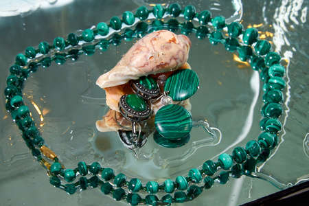 Jewelry from green malachite. Malachite beads in the studio on glass surface with waterの写真素材