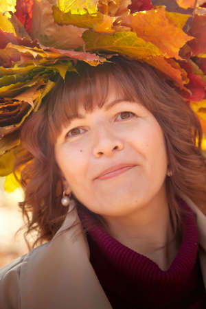 Portrait of mature woman in autumn park and yellow leaves backgroundの写真素材