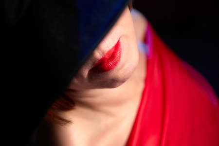 Portrait of ugle middle-aged woman with hat and red dress. Ugly model looking as lady posing in studioの写真素材