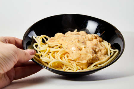 Long spaghetti in a black plate on white backgroundの写真素材