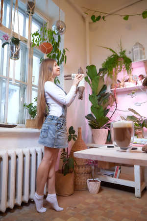 Girl with long hair and with a toy bear in room with a lot of things. Portrait of a young woman in cozy houseの写真素材