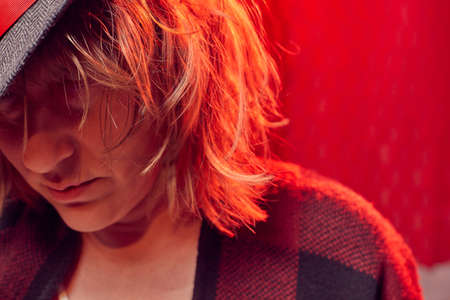 Portrait of serious sad middle-aged woman in hat on red background. Unprofessional female model in the Studioの写真素材