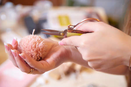 Girl cuts a handmade pompom with scissors. The process of making pompons from threadsの写真素材
