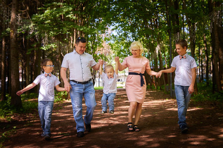 Fun walk of large family in the summer forest. Mother, father, brothers walking in the park or...