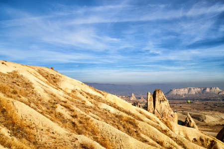 View from top place on the strange landscape in the Cappadocia valley with yellow mountains, rocks and hills and blue sky with white cloudsの写真素材