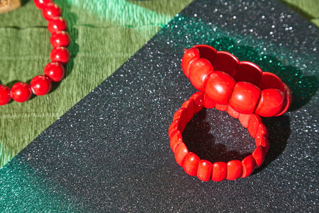 Red beads lying on an unusual surface and a red bracelet