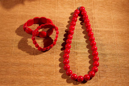 Red beads lying on an unusual surface and a red bracelet