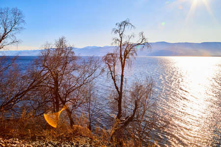 Circum Baikal railway running along the shore of Lake Baikal on an autumn sunny day with a yellow landscape aroundの写真素材