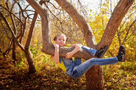 Portrait of young funny girl with blonde curly hair in an autumn park on a yellow and orange leaf backgroundの写真素材