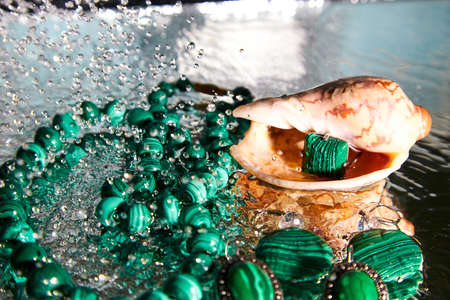 Jewelry from green malachite. Malachite beads in the studio on glass surface with waterの写真素材