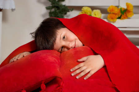 Kirov, Russia - April 25, 2021: Happy young teenager boy at home with red pillow having fun in roomのeditorial素材