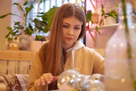 Girl with long hair in a room with a lot of things. Portrait of a young woman in cozy houseの写真素材