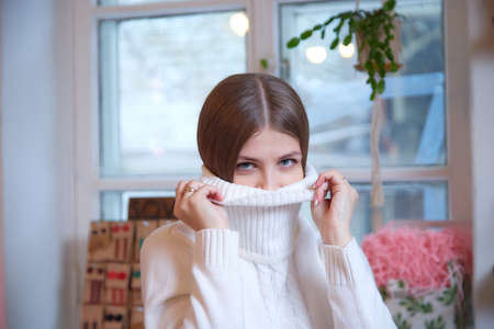 Girl with long hair in a room with a lot of things. Portrait of a young woman in cozy houseの写真素材