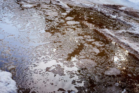 Ice and snow in puddles in spring or autumn time. Thaw after winter in natureの写真素材