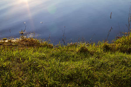 Evening lake and reflection sun in water. Beautiful landscape of river at sunset. The sun is...