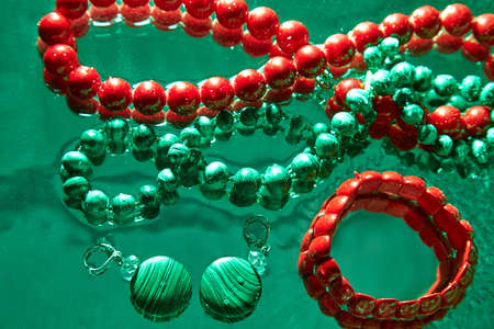 Jewelry from green malachite. Malachite beads in the studio on glass surface with waterの写真素材