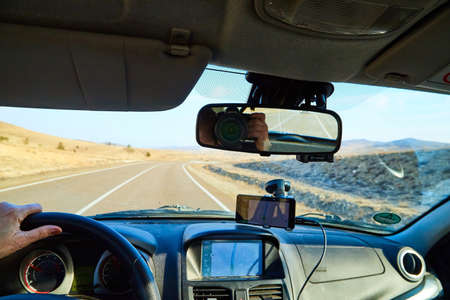 Siberia Baikal, Russia - November 20, 2020: View from of car interior from side of driver to the road and autumn yellow nature landscape with hills through windshieldのeditorial素材