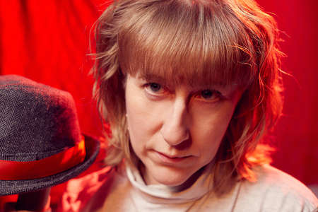 Portrait of serious sad middle-aged woman on red background. Unprofessional female model in the...