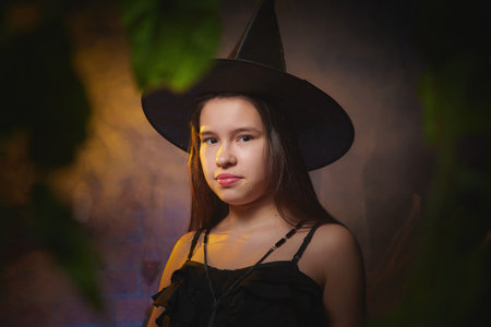 Young girl looking like witch having fun on Halloween in a dark room with yellow light and smoke....