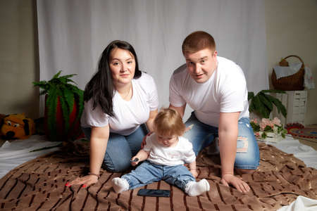 Kirov, Russia - April 25, 2021: Happy family with fat chubby parents and young child in room. Mother, father, boy having fun togetherのeditorial素材