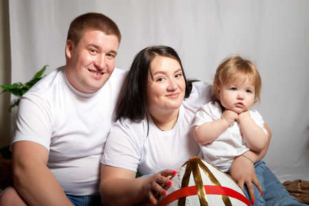 Kirov, Russia - April 25, 2021: Happy family with fat chubby parents and young child in room. Mother, father, boy having fun togetherのeditorial素材