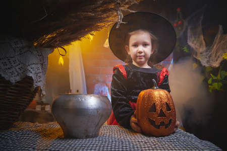Cute little girl in costume for witch in the room decorated fot Halloweenの写真素材