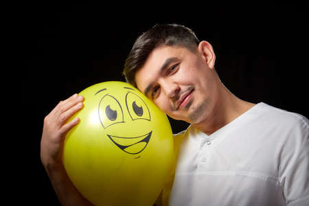 Portrait of a young man in a business suit and wigh with balloons. Positive guy posing in the studio