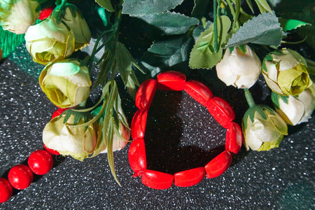 Red beads, red bracelet and flowers on an unusual surface. Beautiful decorationの写真素材