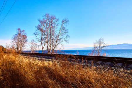 Circum Baikal railway running along the shore of Lake Baikal on an autumn sunny day with yellow...