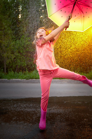 Young funny girl with umbrella under rain in summer dayの写真素材