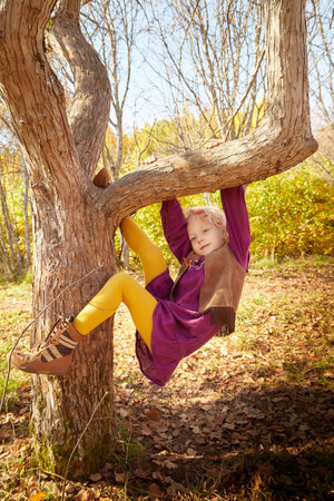 Portrait of young little girl with blonde curly hair in an autumn park on a yellow and orange leaf backgroundの写真素材