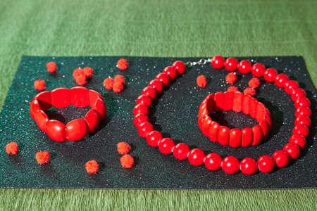 Red beads lying on an unusual surface and red bracelet