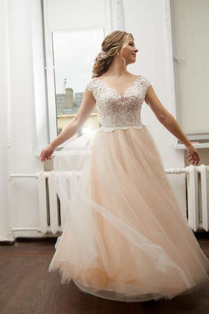 Beautiful bride with a lush hairstyle in a pink dress indoorsの写真素材