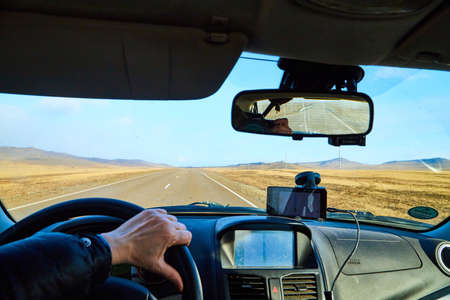 Siberia Baikal, Russia - November 20, 2020: View from of car interior from side of driver to the road and autumn yellow nature landscape with hills through windshieldのeditorial素材