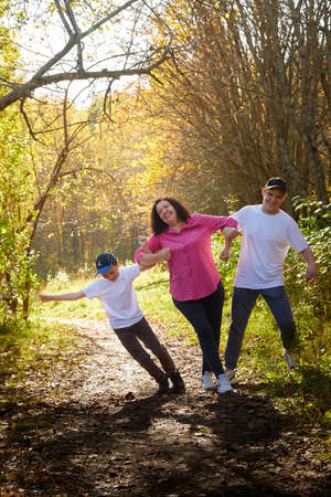Kirov, Russia - September 27, 2020: Mother and sons in autumn park or forest in a sunny day. Happy family walking outdoorsのeditorial素材